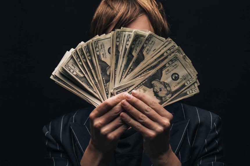 A person holding money in front of their face.